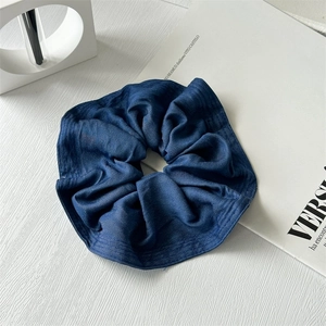 Detail of dark blue denim fabric scrunchie with pleated texture on white background
