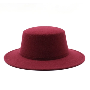 Detail of dark red wool felt flat top hat featuring a wide brim and precision stitching