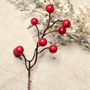 Close-up of artificial red berries for Christmas decoration on rustic linen background