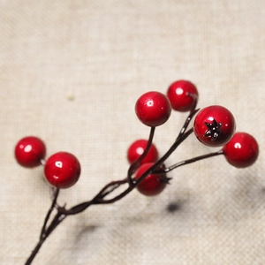 Macro shot of realistic artificial red Christmas berries with glossy finish on jute fabric