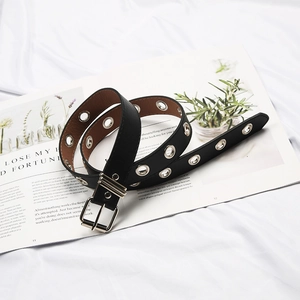 Punk style black leather belt with silver eyelets and single pin buckle on book background