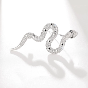 Elegant silver snake brooch set with sparkling cubic zirconia on a white textured background