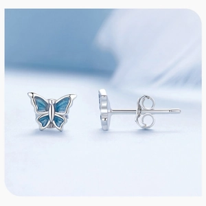 Macro shot of silver butterfly stud earrings with sparkling blue gradient enamel wings