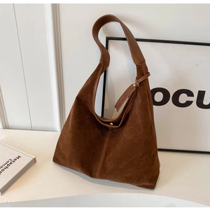Detail of a dark brown suede hobo bag with wide shoulder strap and adjustable buckle