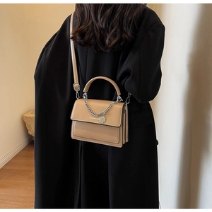 On-body shot of khaki PU leather flap bag featuring silver chain and metal pendant