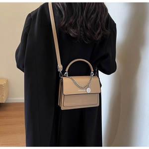 Model view showing the khaki crossbody square bag with a silver chain and pendant