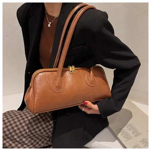 Brown vintage rectangular handbag with twin straps shown on shoulder of a model in suit