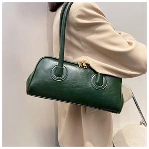 Detail view of a vintage dark green shoulder bag with double gold zippers and slim straps