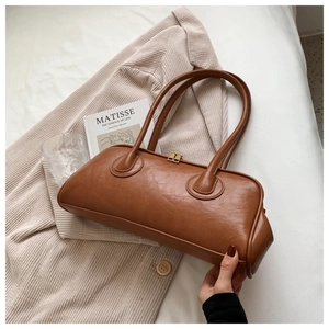 Brown vintage faux leather tote bag with gold double zippers on beige jacket background
