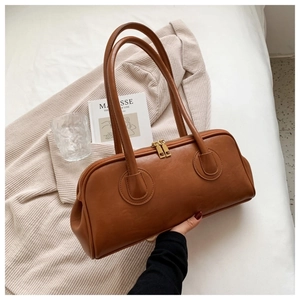 Close-up of a vintage brown leather bowling handbag with gold zipper and dual handles
