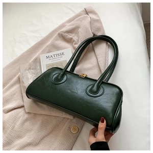 Detail of dark green vintage tote bag with dual handles and gold zipper hardware