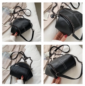 Detail view of black PU leather shell bag with white cross stitching and kiss lock closure