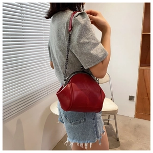 Side view of dark red vintage shell chain bag worn over the shoulder by a model