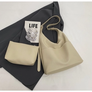 Detail of beige PU leather bucket bag set with matching pouch on a grey blazer and magazine