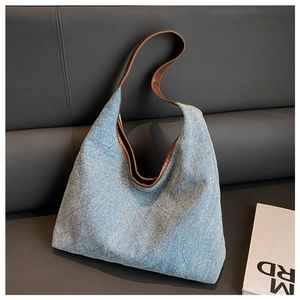 Detail of blue denim tote bag with brown handles and classic diamond quilted texture
