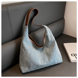 Detail of blue denim tote bag with diamond quilted pattern and brown leather strap