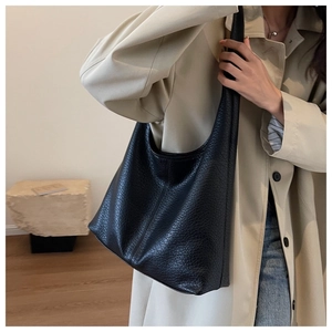 Detailed view of black pleated leather tote bag showing soft texture and slouchy drape