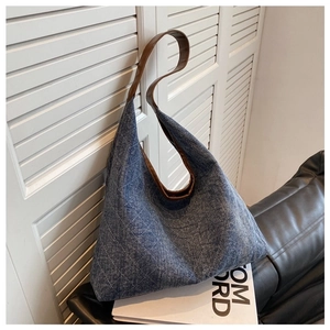 Detail showing blue denim tote bag with diamond quilting and brown leather strap