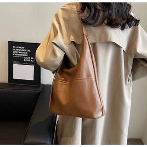 Detail of a large brown faux leather bucket bag with visible side pocket stitching