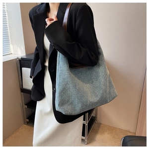 Lifestyle view of a large light blue denim tote bag with brown leather straps