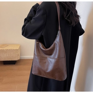 Deep brown bucket bag styled over a black coat showing large capacity and smooth texture