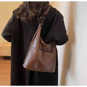 Detail view of large dark brown faux leather bucket bag with two functional external pockets
