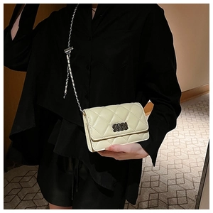 Close-up of quilted pattern and silver chain on a pale yellow crossbody square bag