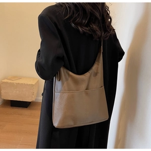 Detail view of large brown bucket bag showing pebbled leather texture and front pockets
