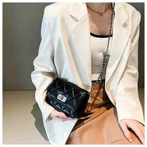 Detail view of black quilted chain bag with metallic turn-lock on a model