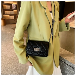 Mini black quilted chain bag with silver lock worn with a stylish lime green blazer