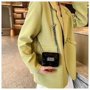 Close-up of a black quilted crossbody bag with gold chain and silver lock on a model