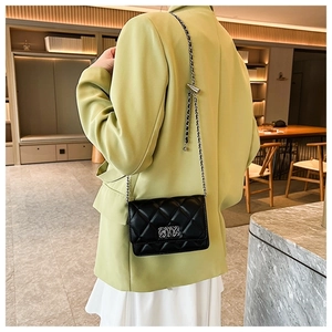 Detail of silver chain strap and metal clasp on black quilted small square crossbody bag