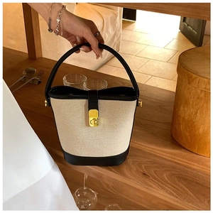 Detailed view of canvas bucket bag with black leather trim and golden metal clasp