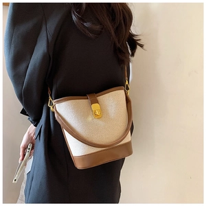 Side view of a vintage contrast canvas and leather bucket bag with gold hardware buckle