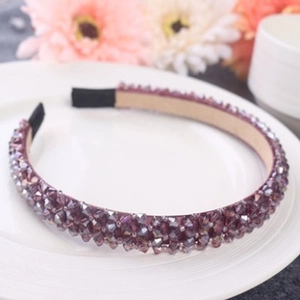 Detailed view of a purple crystal headband with faceted beads on a white tray