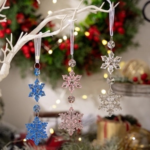 Colorful acrylic snowflake ornaments in blue and pink hanging on a Christmas tree