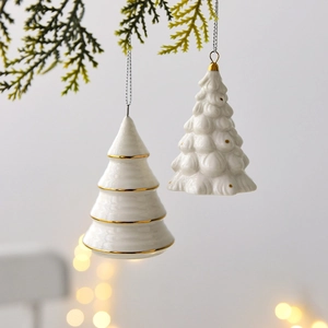 Mini ceramic Christmas tree hanging ornaments with gold details on a pine branch background