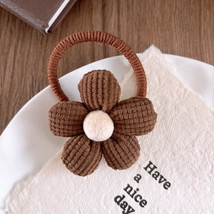 Detail of brown corduroy flower hair tie with cream plush center on decorative plate