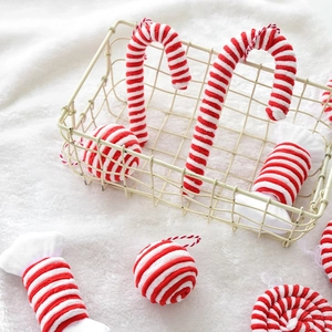 Red and white velvet Christmas ornaments including candy canes and balls in a basket