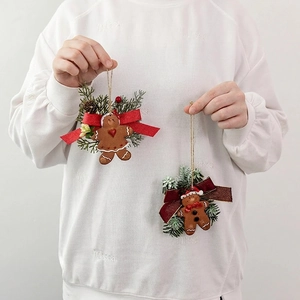 Pair of festive gingerbread man ornaments with PE pine needles and red bows for Christmas tree