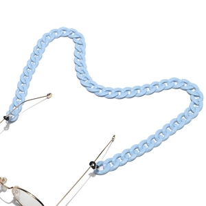 Close-up of light blue acrylic chain links attached to gold metal glasses frames