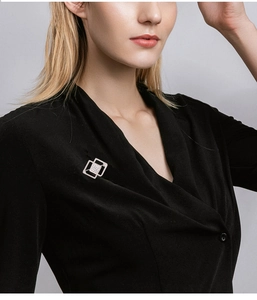 Detail view of a silver geometric cube brooch with sparkling rhinestones on a black top
