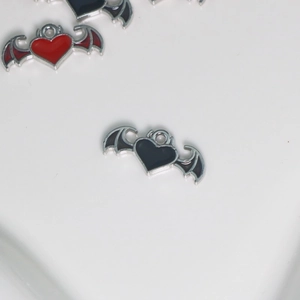 Detailed macro view of gothic heart charms with silver wings in red and black enamel