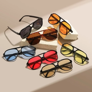 Classic pilot double-bridge sunglasses with colorful lenses shown on textured stones