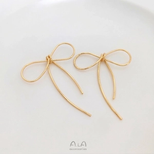 Dettaglio di ciondoli a fiocco in oro 14K fatti a mano con finitura in filo metallico