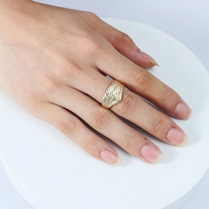Detailed view of the golden angel wing ring with intricate feather texture on a finger