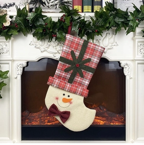 Detailed view of a snowman Christmas stocking with red plaid hat hanging on a festive fireplace