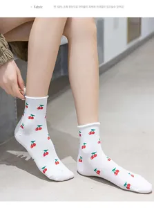 Detail of white cotton mid-calf socks with cute red cherry pattern and ruffled edge