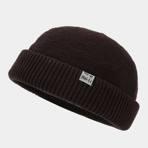 Detail of a brown knitted miki hat showing the texture and the side textile label