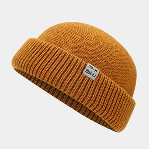 Retro mustard yellow knitted docker hat with a small logo patch in a 45-degree angle view